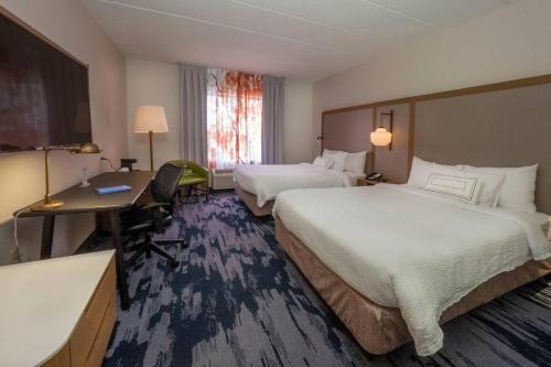 a hotel room with two beds and a desk at Fairfield Inn by Marriott Hazleton in Hazleton
