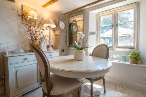 a dining room with a table and chairs and clocks at Cottage on the Dart- Riverside Fishermans Cottage in Stoke Gabriel