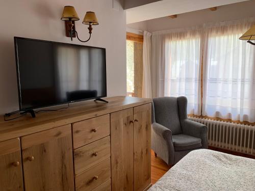 1 dormitorio con TV en un tocador con silla en Casa Margarita, en Sesué