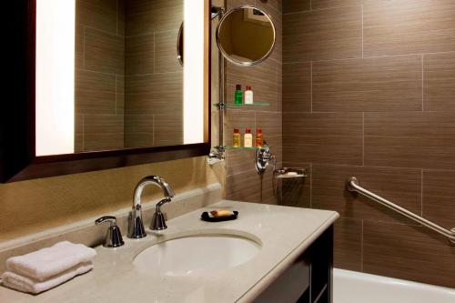 a bathroom with a sink and a mirror and a tub at Sheraton Brooklyn New York in Brooklyn