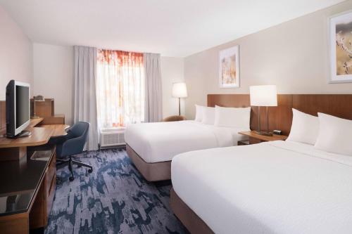 a hotel room with two beds and a desk and a television at Fairfield Inn and Suites Austin South in Austin