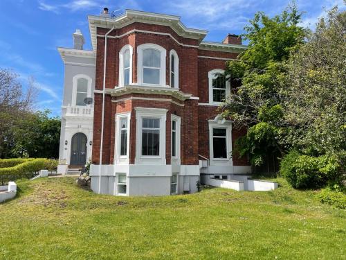 a large red brick house with a grass yard at Beach House 3 Bed Penthouse Apartment in Southport