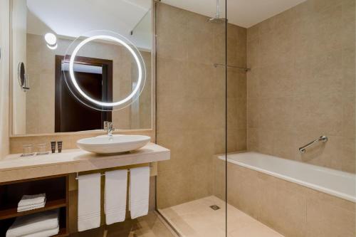 a bathroom with a sink and a mirror and a tub at Sheraton Poznan Hotel in Poznań