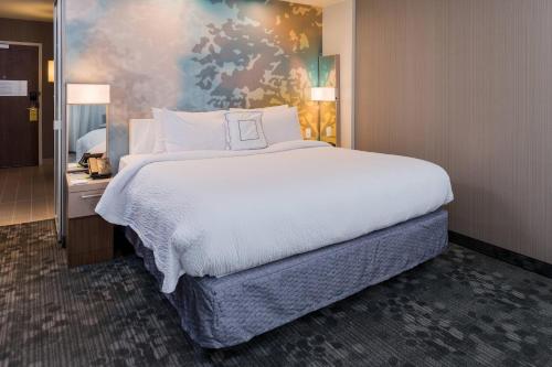 a bedroom with a large bed with white sheets at Courtyard by Marriott Elmira Horseheads in Horseheads