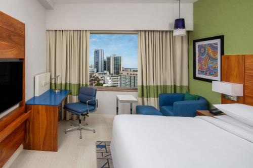 a hotel room with a bed and a desk and chairs at Four Points by Sheraton Dar es Salaam New Africa in Dar es Salaam