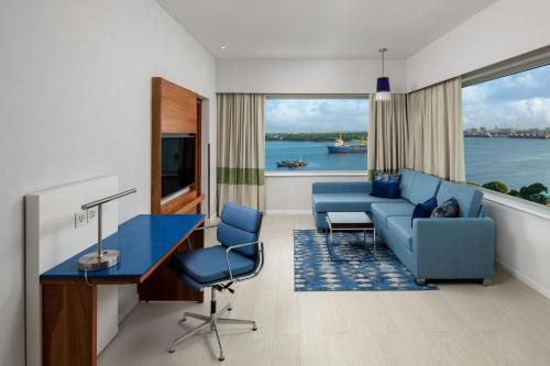 a living room with a blue couch and a table and chairs at Four Points by Sheraton Dar es Salaam New Africa in Dar es Salaam