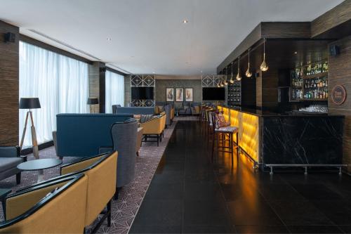 a restaurant with a bar with chairs and tables at Four Points by Sheraton Dar es Salaam New Africa in Dar es Salaam