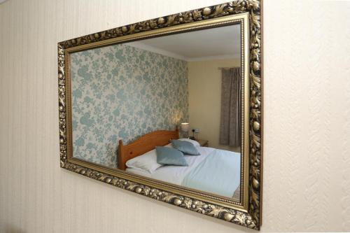a mirror hanging on a wall with a bed at Dorset Hotel, Isle of Wight in Ryde