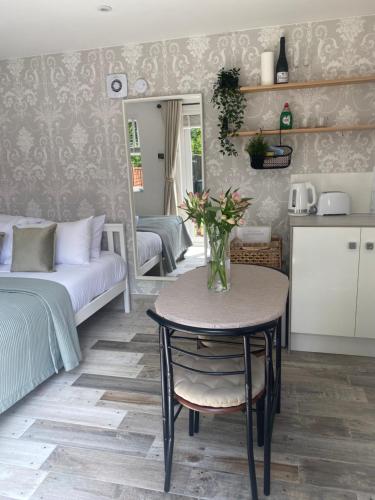 een kamer met een tafel en een bed en een keuken bij The Garden room in Honiton