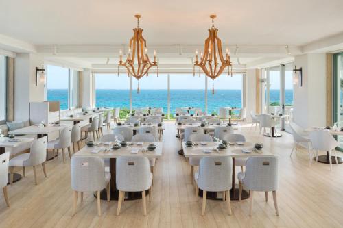 a dining room with tables and chairs and the ocean at IRAPH SUI, a Luxury Collection Hotel, Miyako Okinawa in Miyako Island