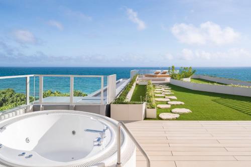 a bath tub on the balcony of a house overlooking the ocean at IRAPH SUI, a Luxury Collection Hotel, Miyako Okinawa in Miyako Island