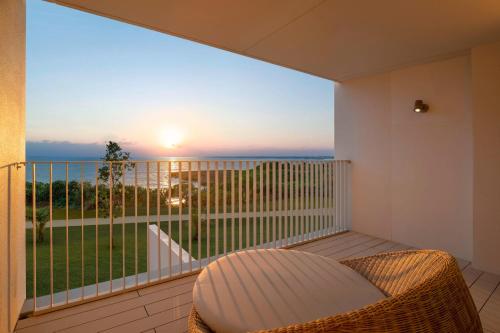 宮古島的住宿－IRAPH SUI, a Luxury Collection Hotel, Miyako Okinawa，阳台配有藤椅,享有海景。