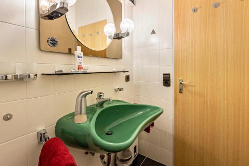 a bathroom with a green sink and a mirror at Terrassenpark Schonach App 161 in Schonach