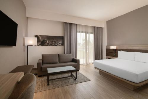ein Hotelzimmer mit einem Bett und einem Sofa in der Unterkunft AC Hotel by Marriott Punta Cana in Punta Cana