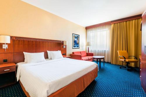 a hotel room with a large bed and a red chair at Courtyard by Marriott Prague City in Prague