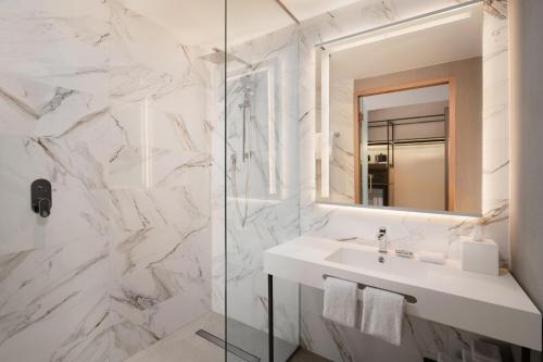 a white bathroom with a sink and a mirror at AC Hotel by Marriott Punta Cana in Punta Cana