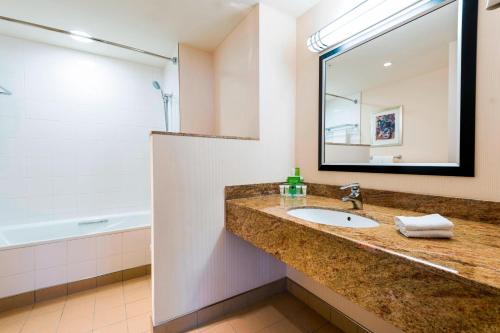 a bathroom with a sink and a mirror and a tub at Courtyard by Marriott Prague City in Prague