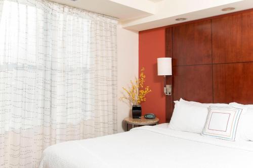 1 dormitorio con cama blanca y pared roja en Residence Inn Moline Quad Cities, en Moline