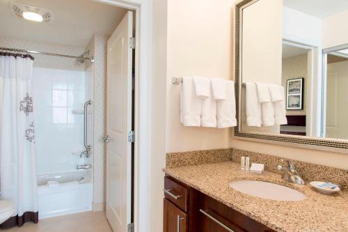 a bathroom with a sink and a mirror and a shower at Residence Inn Moline Quad Cities in Moline