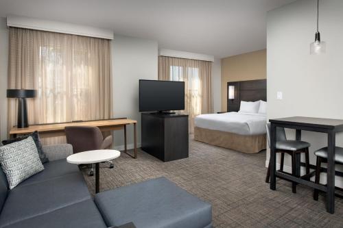 a hotel room with a couch and a bed and a television at Residence Inn by Marriott Phoenix Airport in Phoenix
