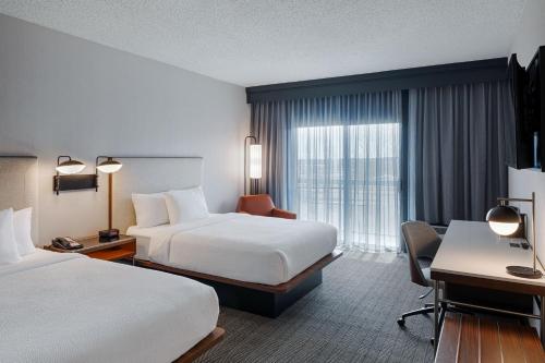 a hotel room with two beds and a desk at Courtyard Dayton South Mall in Miamisburg