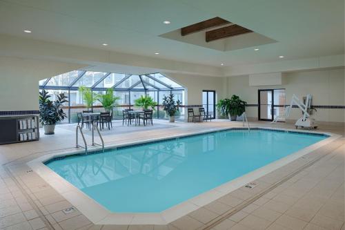 a large swimming pool in a building with a table and chairs at Courtyard Dayton South Mall in Miamisburg