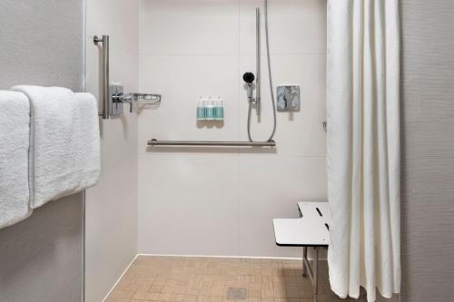 a bathroom with a shower and a sink and towels at Courtyard by Marriott Rye in Rye