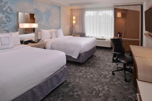 ein Hotelzimmer mit zwei Betten und einem Schreibtisch in der Unterkunft Courtyard by Marriott Boston Littleton in Littleton