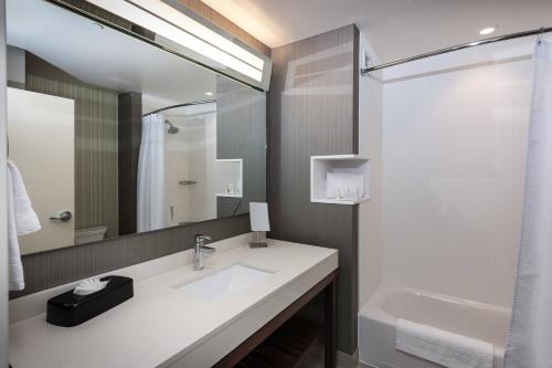 Baño blanco con lavabo y espejo en Courtyard by Marriott Boston Littleton en Littleton