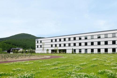 un grand bâtiment blanc avec une pelouse devant lui dans l'établissement Fairfield by Marriott Hokkaido Minamifurano, à Minamifurano