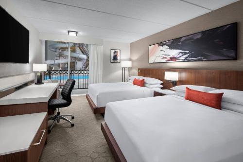 Habitación de hotel con 2 camas, escritorio y TV. en Delta Hotels by Marriott Green Bay en Green Bay