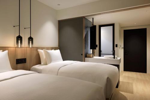 two white beds in a room with a mirror at Fairfield by Marriott Hokkaido Minamifurano in Minamifurano