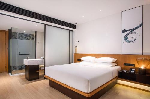 een slaapkamer met een wit bed en een wastafel bij Fairfield by Marriott Foshan Nanhai in Foshan