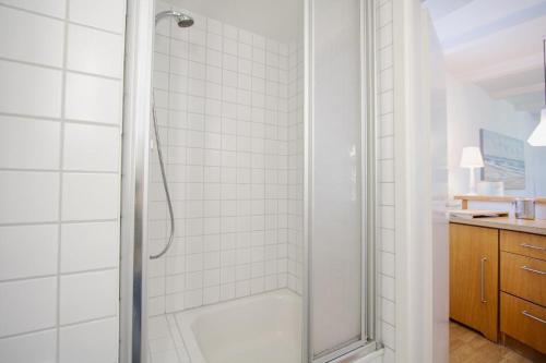ein Bad mit einer Dusche und weißen Fliesen in der Unterkunft kleines Versteck- Ein ganz besonderes Domizil inmitten der Friedrichstraße in Westerland