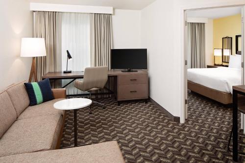 a hotel room with a couch and a bed and a television at Residence Inn Boston Dedham in Dedham