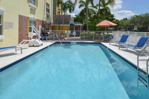 TownePlace Suites Miami Lakes في ميامي ليكس: مسبح ازرق كبير مع كراسي ومظلة