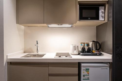 eine kleine Küche mit einer Spüle und einer Mikrowelle in der Unterkunft العنوان للشقق المخدومة-The Address Residence in Khobar
