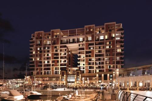 un grand bâtiment avec des lumières en face d'un port de plaisance dans l'établissement The Ritz-Carlton, Herzliya, à Herzliya