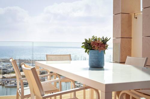 a white table with chairs and a vase with flowers at The Ritz-Carlton, Herzliya in Herzelia 