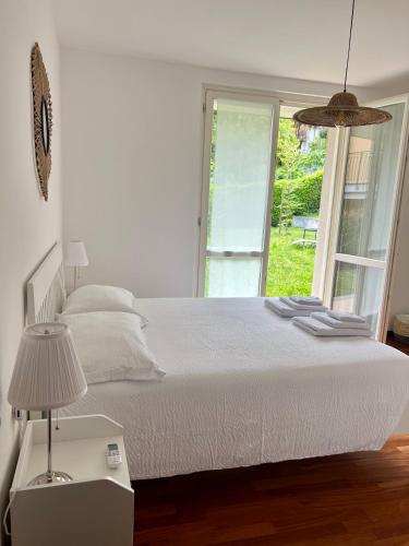 een witte slaapkamer met een bed en een raam bij giardino e piscina apartment in Bellagio