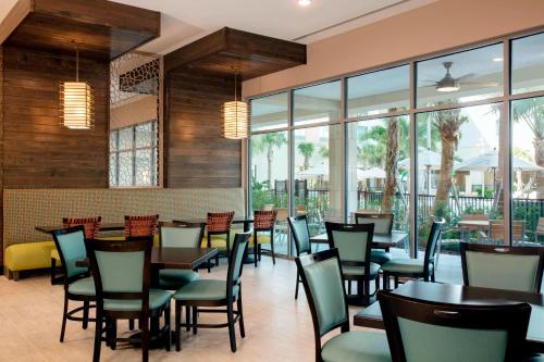 Un restaurante con mesas, sillas y ventanas. en TownePlace Suites by Marriott Orlando Theme Parks Lake Buena Vista, en Orlando