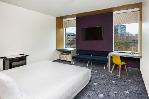 シャーロットにあるAloft Charlotte Ballantyneのベッド、デスク、テレビが備わるホテルルームです。