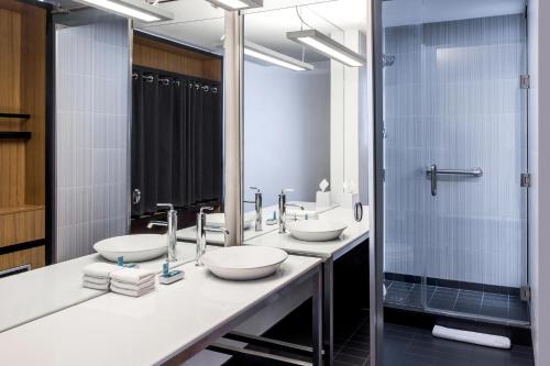 a bathroom with two sinks and a shower at Aloft Charlotte Ballantyne in Charlotte