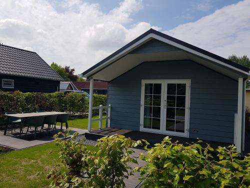 a small blue house with a table in the yard at De Bijsselse Enk, Noors chalet 19 in Nunspeet