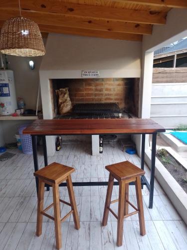 une table et deux tabourets devant une cheminée dans l'établissement Hospedaje La Calma, à San Miguel del Monte