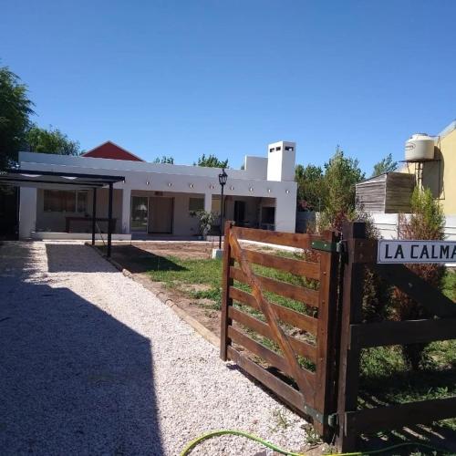 una valla frente a una casa con un edificio en Hospedaje La Calma en San Miguel del Monte