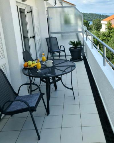eine Terrasse mit einem Tisch und Stühlen auf dem Balkon in der Unterkunft Apartman Marko in Nečujam