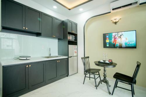 a kitchen with black cabinets and a table and chairs at SAZI BEN THANH Hotel HCM in Ho Chi Minh City