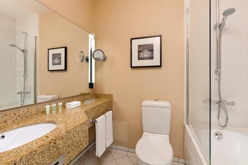 a bathroom with a toilet and a sink and a shower at Courtyard by Marriott Düsseldorf Seestern in Düsseldorf