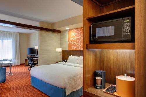 Fairfield Inn & Suites by Marriott Lincoln Southeast في لينكولن: غرفة فندقية بسرير وتلفزيون بشاشة مسطحة